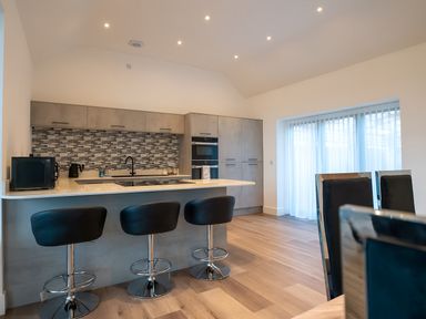 A kitchen with bar stools and cabinets at The Shearling in Morpeth