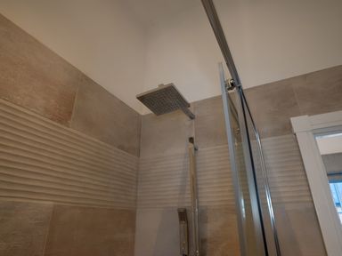 A shower with a glass door and wall tiles at The Shearling in Morpeth