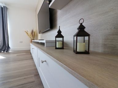 A living room with a tv and lanterns on a shelf at The Newland in Morpeth