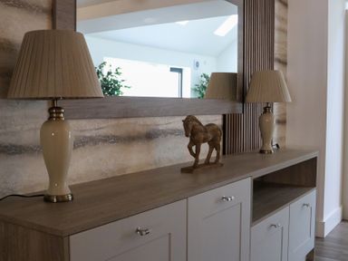A living room with a console table, lamps, and a horse sculpture at The Newland in Morpeth
