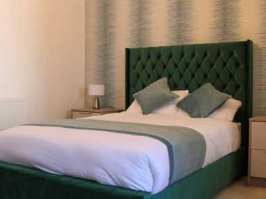 A bedroom with a green headboard and white bedding at The Newland in Morpeth