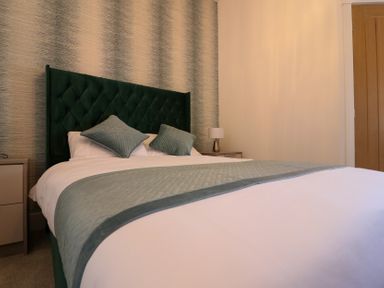 A bedroom with a bed and green headboard at The Newland in Morpeth