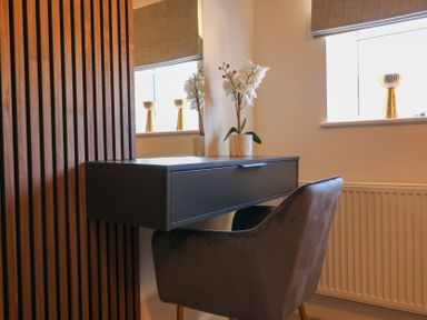 A desk with a chair and a flower vase under a window at The Newland in Morpeth