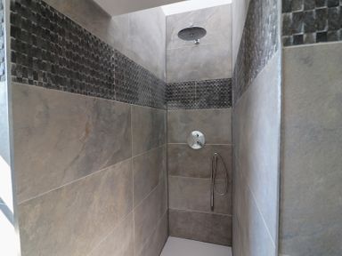 A shower with tile walls and a shower head at The Newland in Morpeth