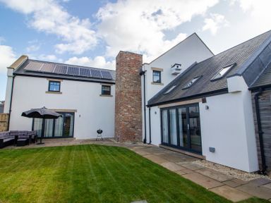 A house with solar panels and outdoor seating in the garden at The Newland in Morpeth