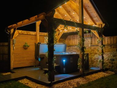 A garden with a hot tub under a wooden gazebo at The Newland in Morpeth
