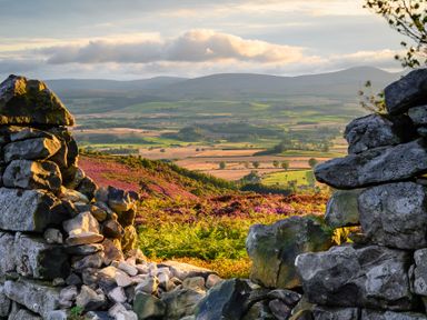 A stone wall framing a view of mountains and fields at The Newland in Morpeth