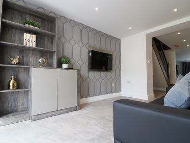 A living room with a shelf, TV, and decorative items at The Gavel in Morpeth