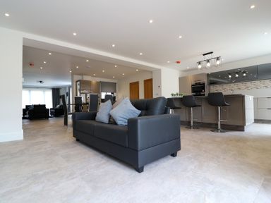 A living room with a black couch and kitchen area at The Gavel in Morpeth