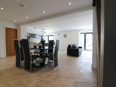 A dining room with a table and chairs adjacent to a living area at The Gavel in Morpeth