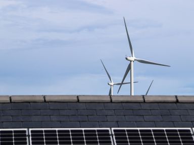 Wind turbines visible above a roof with solar panels