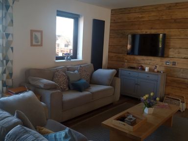 A living room with a couch, television, and coffee table at Gowrie Lodge in Blairgowrie