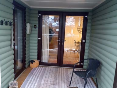 A porch with double doors and a chair at Gowrie Lodge in Blairgowrie