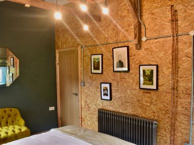 A bedroom with a yellow sofa and framed pictures at Ty Llaeth in Carmarthen