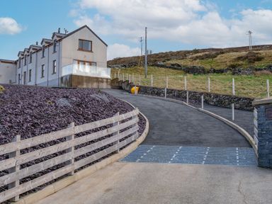 A house with a driveway and fence at Groeslon Uchaf in Caernarfon