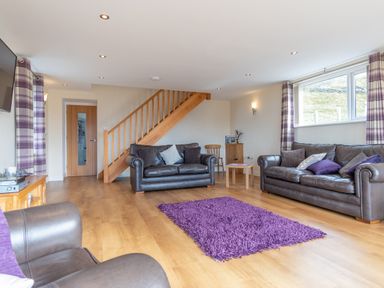 A living room with sofas and a rug at Groeslon Uchaf in Caernarfon