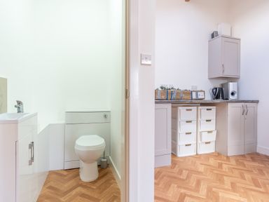 A bathroom with a toilet and sink alongside a kitchen area at Groeslon Uchaf Caernarfon