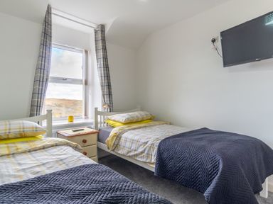 A bedroom with two beds and a television at Groeslon Uchaf in Caernarfon