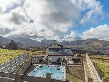 An outdoor area with a hot tub and a house at Groeslon Uchaf in Caernarfon