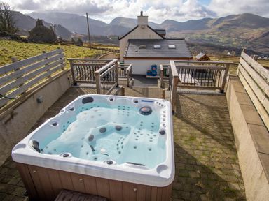 An outdoor area featuring a hot tub with a view of mountains at Groeslon Uchaf, Caernarfon