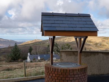 A well with a roof in a rural landscape at Groeslon Uchaf in Caernarfon
