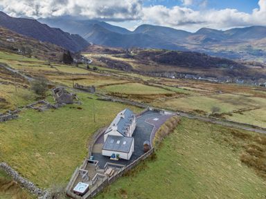 An outdoor view of a house with a spa and surrounding fields at Groeslon Uchaf in Caernarfon