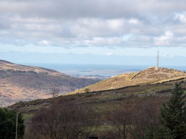 A view of mountains and a telecommunications tower near the ocean at Groeslon Uchaf in Caernarfon