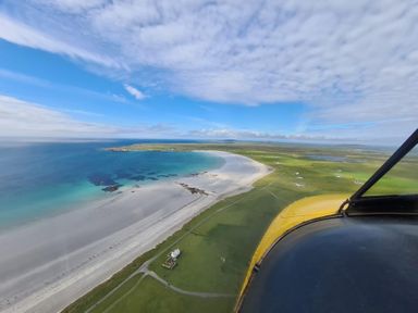 An aerial view of a beach and green land at Kirkapol Beach Pod - Flow Isle of Tiree