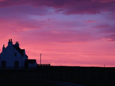 A house silhouette against a colorful sky at Kirkapol Beach Pod - Flow Isle of Tiree