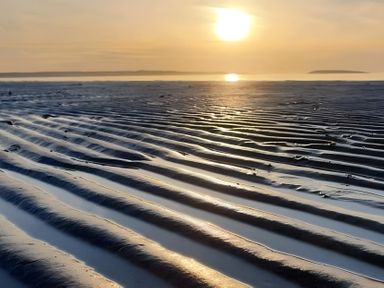A beach with rippled sand and sunlight at Blue Haven Penmaenmawr