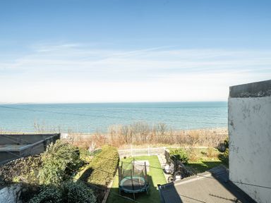 A view of the sea and garden with a trampoline at Blue Haven in Penmaenmawr