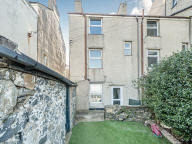 A garden with a building and stone wall at Blue Haven in Penmaenmawr