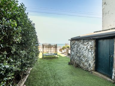 A garden with a trampoline and hedge at Blue Haven in Penmaenmawr