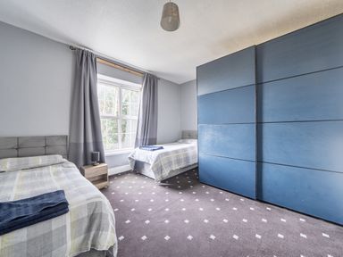 A bedroom with two beds and a wardrobe at Sea View Escape in Penmaenmawr