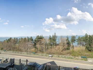 A view of the ocean surrounded by trees at Sea View Escape in Penmaenmawr