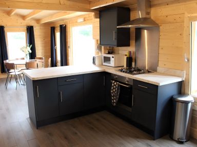 A kitchen with black cabinets and a dining table at Cotswold Nights Away 1 Evesham