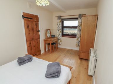 A bedroom with a bed and wooden furniture at Sunny Brae in Alnwick