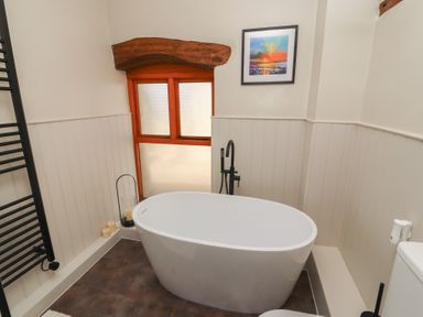 A bathroom with a bath tub and a towel rail at Tullythwaite Barn in Kendal