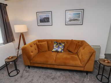 A living room with a sofa and lamp at 1 Sunnybrae in Alnwick