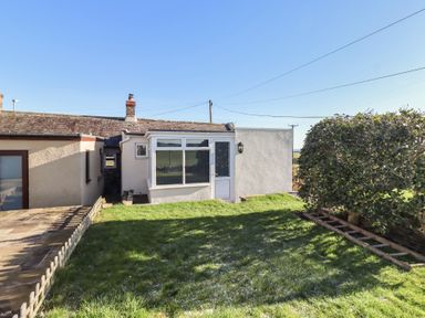 An outdoor view of a cottage with a door and window at Harry's Cottage in Embleton