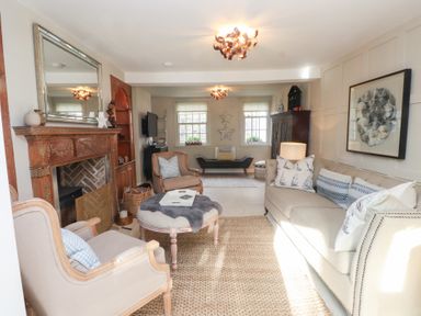 A living room with a sofa, armchair, and coffee table at The Music Box in Beaumaris