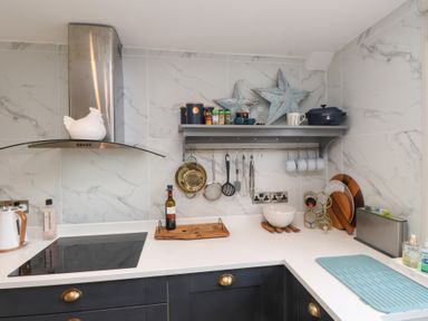 A kitchen with cooking utensils and a shelf at The Music Box in Beaumaris