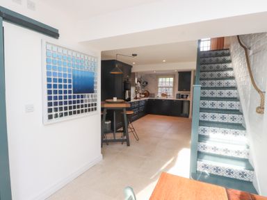 A kitchen with a staircase and dining area at The Music Box in Beaumaris