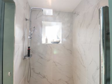 A shower with a window and soap dispenser at The Music Box Beaumaris