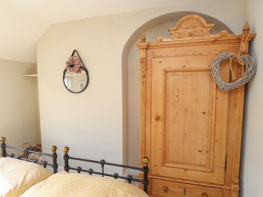 A bedroom with a bed and wardrobe at The Music Box in Beaumaris