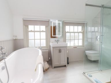 A bathroom with a bathtub, sink, and shower at The Music Box in Beaumaris