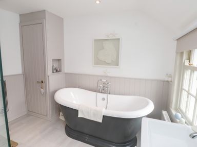 A bathroom with a freestanding bathtub and a sink at The Music Box in Beaumaris