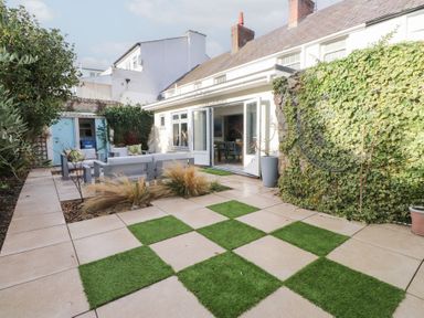 A garden area with outdoor seating and grass patches at The Music Box in Beaumaris