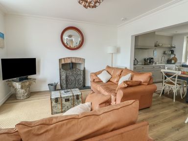 A living room with a television and sofa at Tri Raglan Mawr in Beaumaris