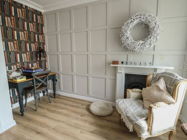 A living room with a chair and table at Tri Raglan Mawr Beaumaris
